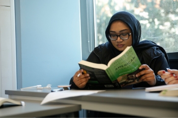 Single female student reading a book in a classroom at Hertfordshire International College